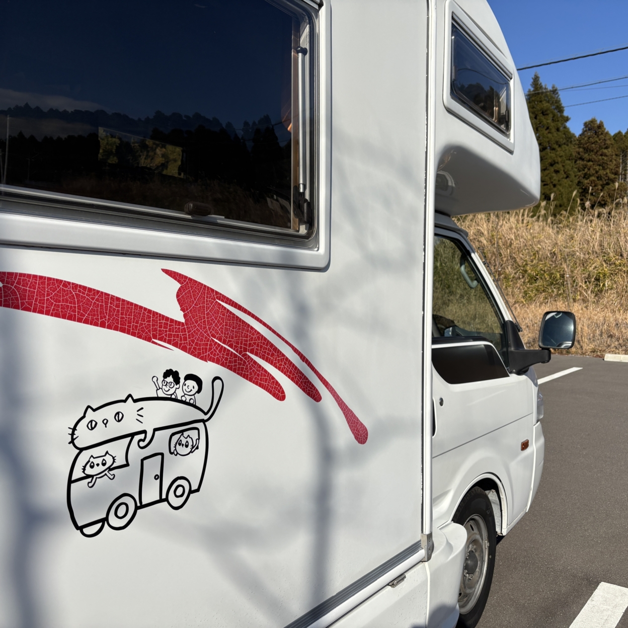 キャンピングカーに貼られた、猫とキャンピングカーのデザインのステッカー
